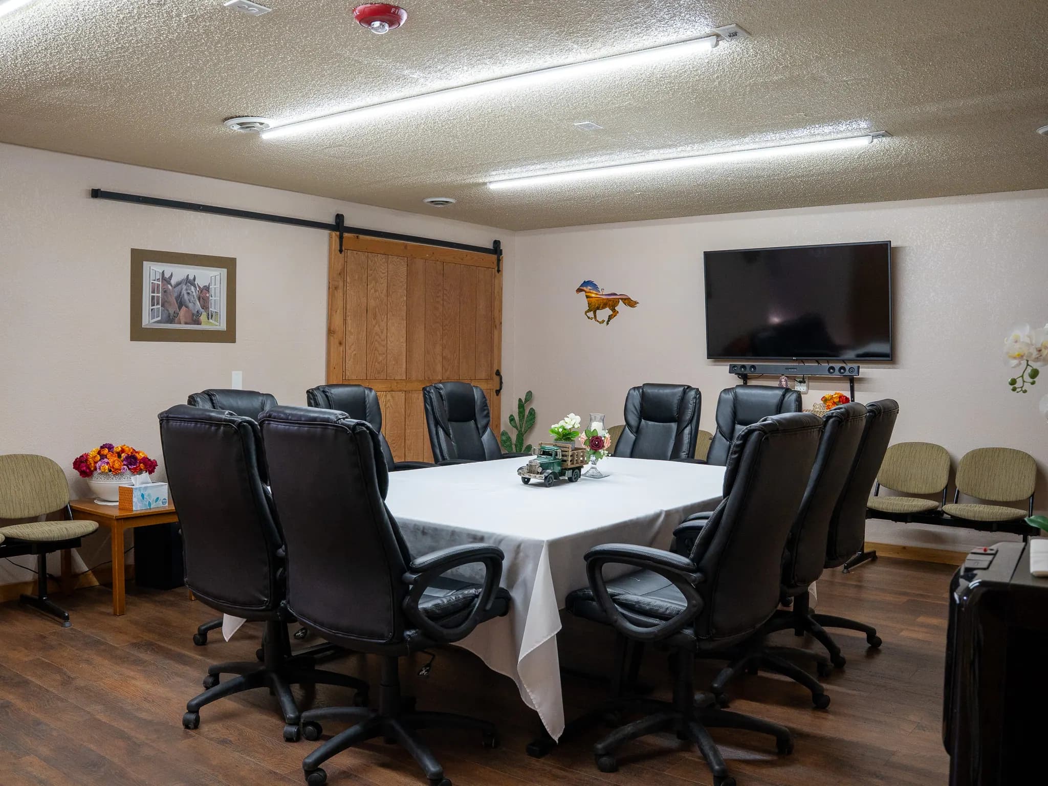 Boardroom meeting table with wall-mounted TV and horse artwork